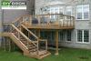 Large high single level deck attached to the back of a grey brick home.