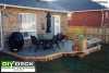Low medium size single level deck attached to a brown brick house with a BBQ, and a table and chairs.