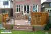 Large 2-level deck with planters a bench and a privacy screen attached to a red brick house.